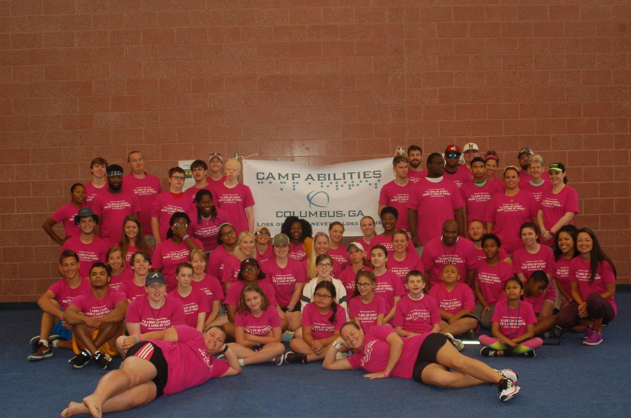 group photo of the 2017 Camp Abilities campers posing with a large sign of the Camp Abilities logo