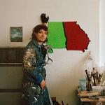 Artist Dom Smith posing in studio with Georgia state-shaped artwork on wall