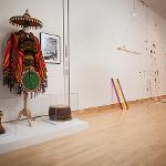 Mixed media assemblage sculpture with headdress and colorful sticks in gallery