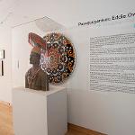 Circular portrait painting of Eddie Owens Martin displayed on pedestal with wall text