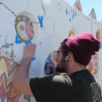 Two artists painting detailed designs on a white wall mural.