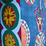 Close-up of painted wall mural with floral medallions, a figure, and a cross