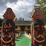 Painted totems with face designs flanking the walkway entrance to the main house