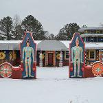 Snow-covered Pasaquan entrance with two painted figure totems flanking the gate