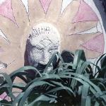 Sculpted face medallion with sunburst pattern partially hidden by plants