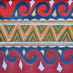 Close-up of painted wall with red and blue spiral wave and green chevron patterns