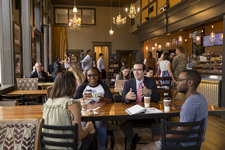 Several students and a professor talking at a table