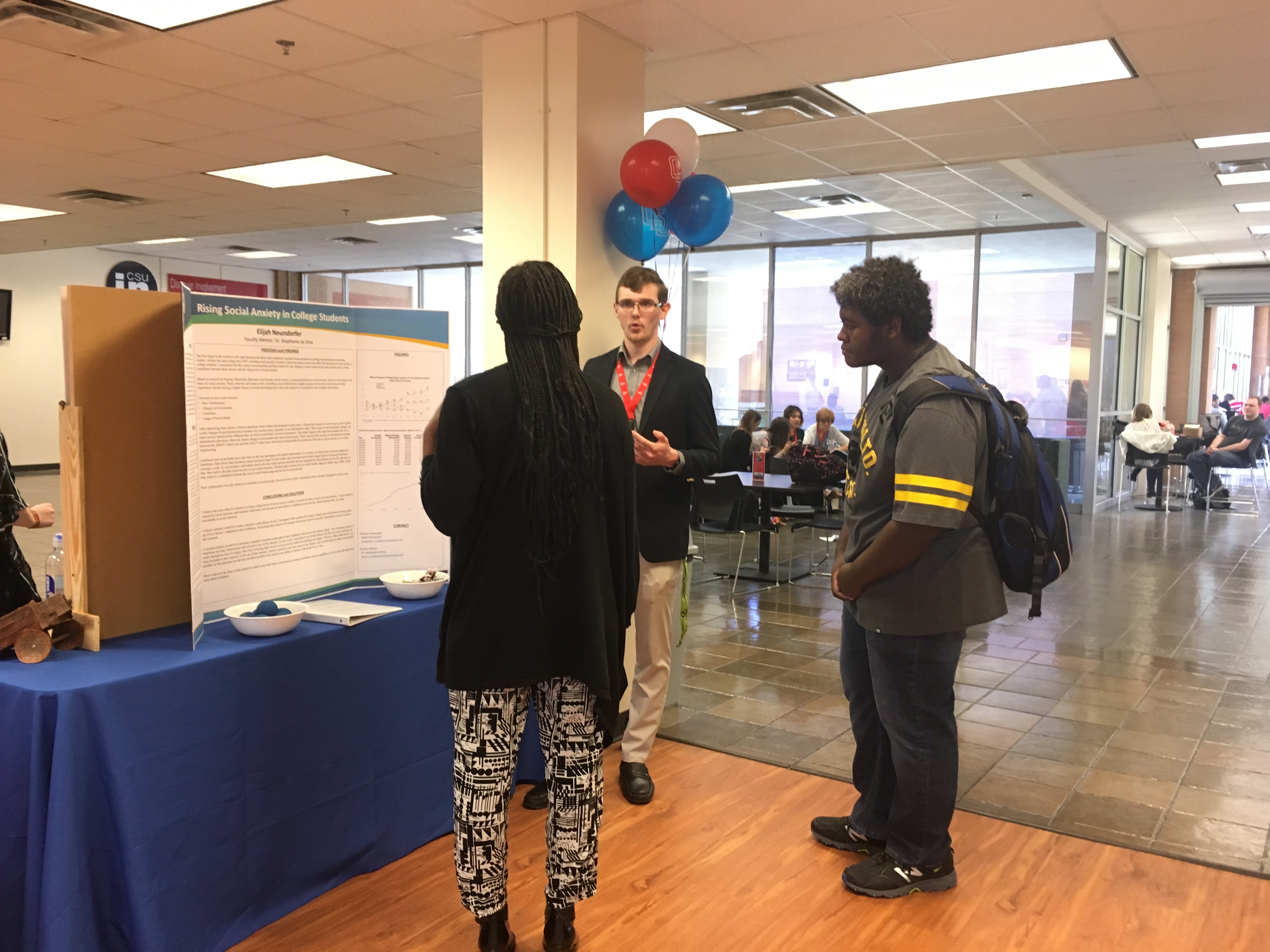 a student talking about a poster with two other students
