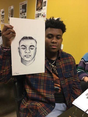 Male student showing his drawing from art lab