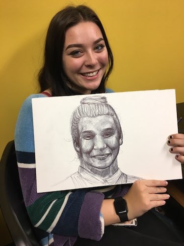 Female student showing her drawing from art lab