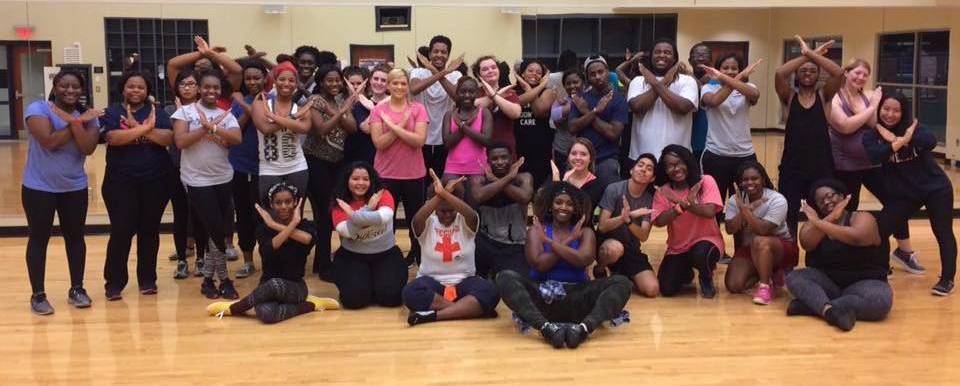 students and group fitness instructors posing together with arms crossed in an X