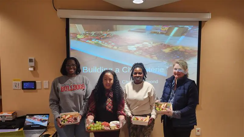 four women showing off their charcuterie board creations