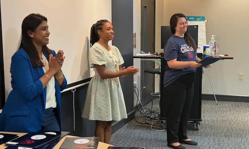 Three teachers standing at the front of a classroom talking to students