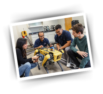 Four people looking at a small robot