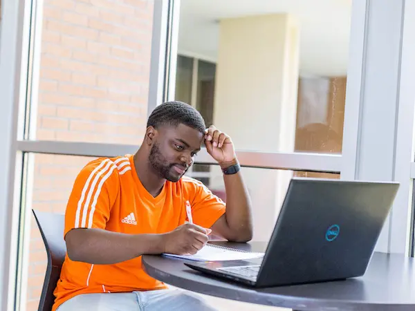 a male student sitting a table with his laptop