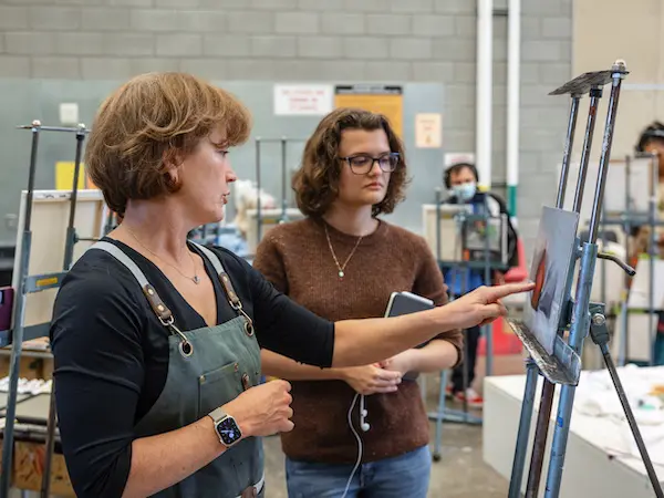 professor giving a student instruction about her painting she is working on
