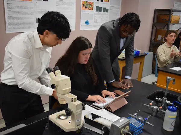 3 students working on a microscope