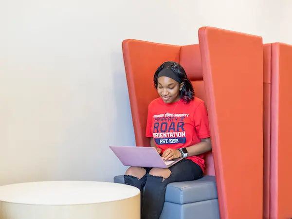 student sitting in a chair with her laptop