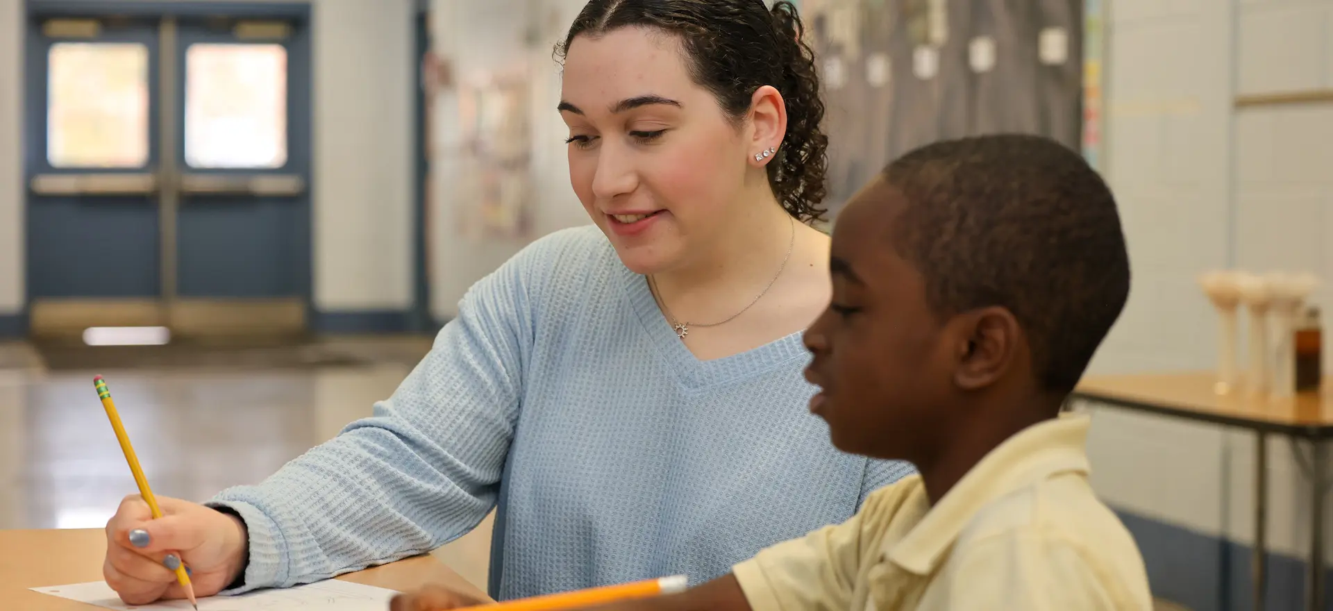 Student teacher teaching a young boy at an elementary school
