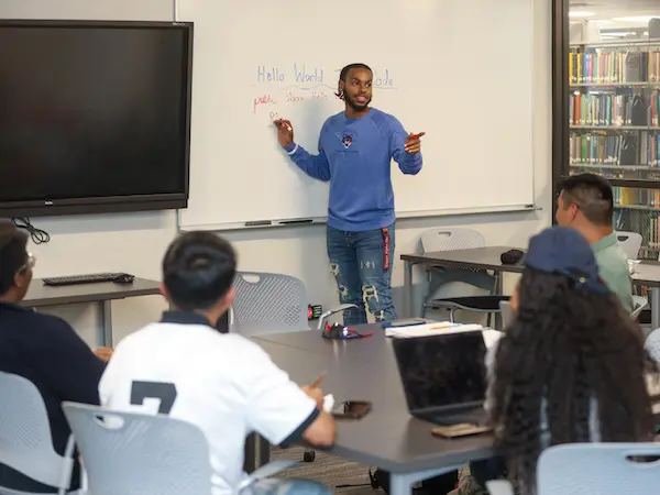 a student at a whiteboard teaching a class