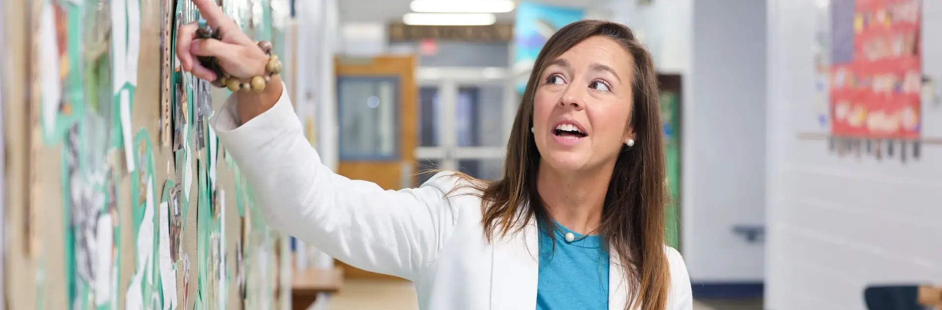 a teacher explaining something at a bulletin board
