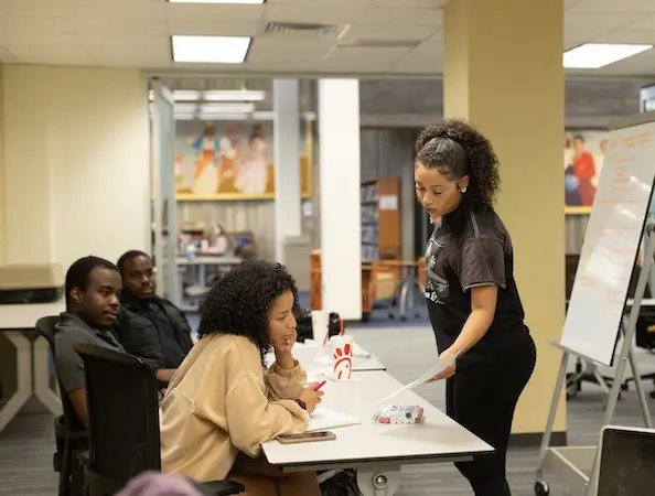 a teacher explaining something to 3 students