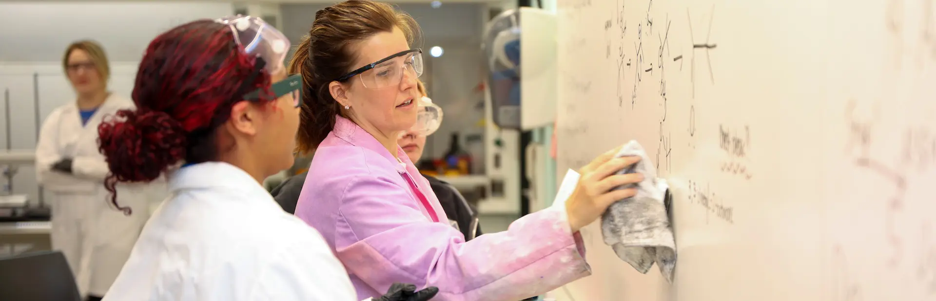 A professor at a white board with a student
