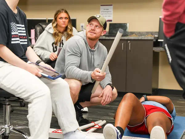 A professor teaching his students while they are gathered around him.