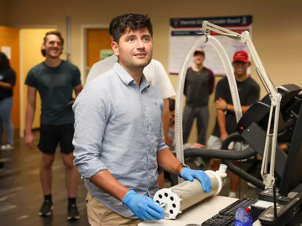 A student wearing gloves is learning how to use a machine.