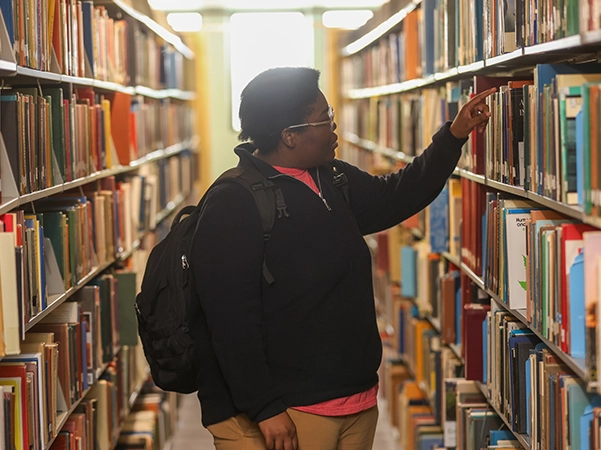A student looking through books in the library.