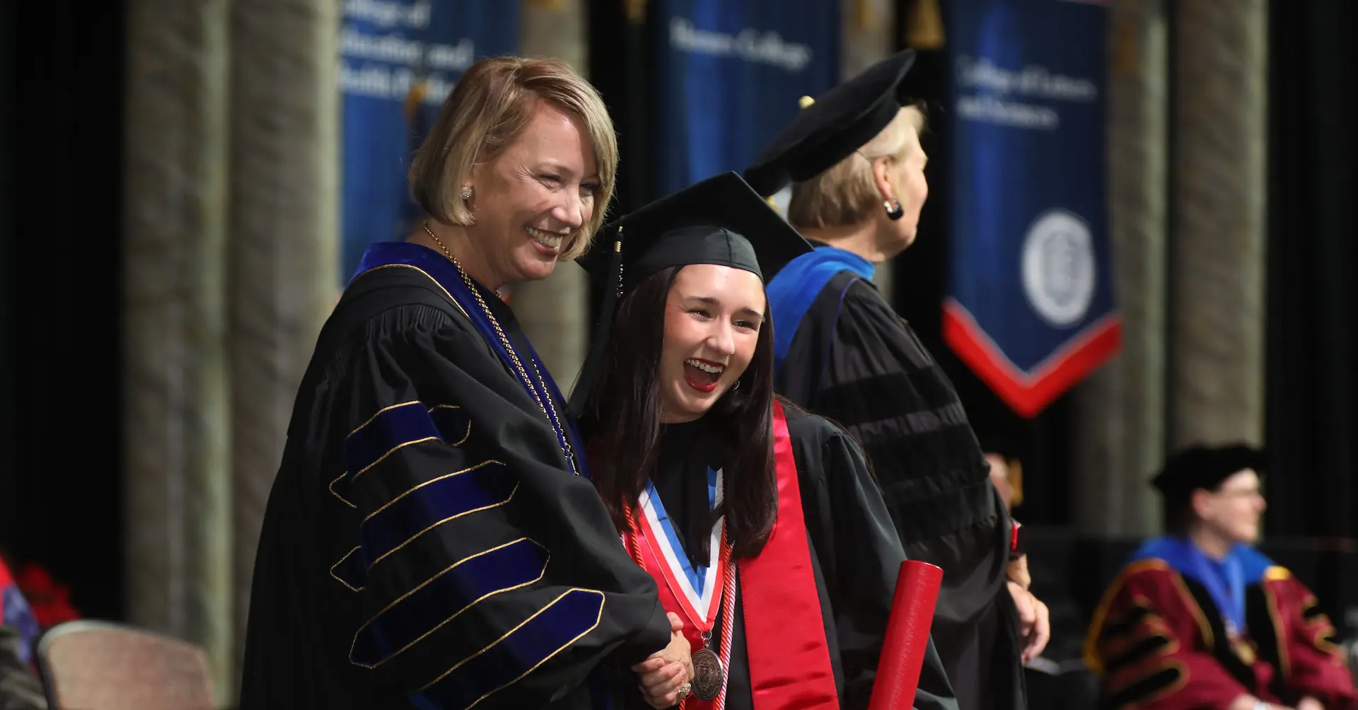 Dr. Rayfield shaking hands with a student at graduation