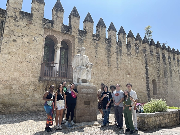 Students posing for a photo beside a statue at Alcazar Seville.
