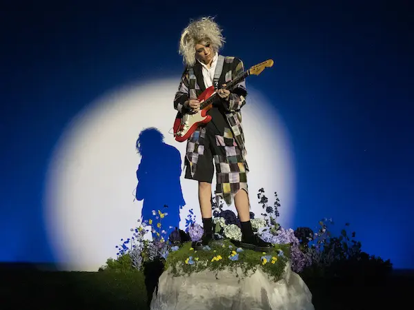 a theatre student on stage with a guitar