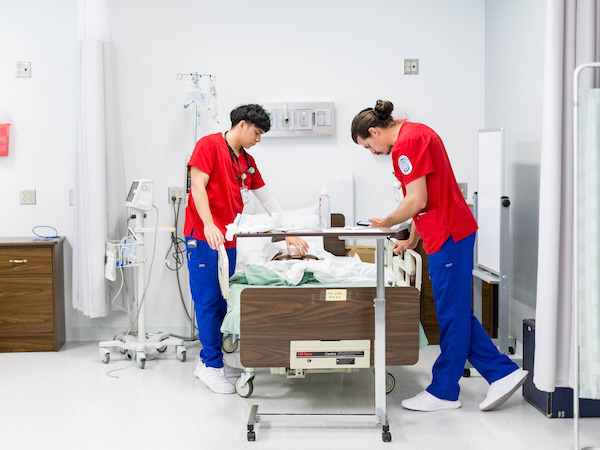 Two nursing students practicing caring at hospital bed