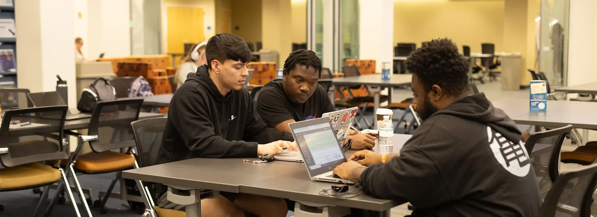 three students at a table studying