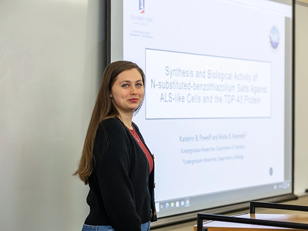 A professor standing by her presentation as she prepares to teach her class.
