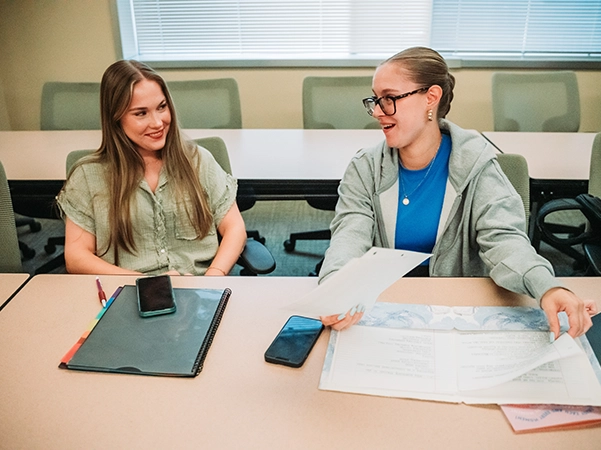 Two students in a bright classroom enjoying studying together.