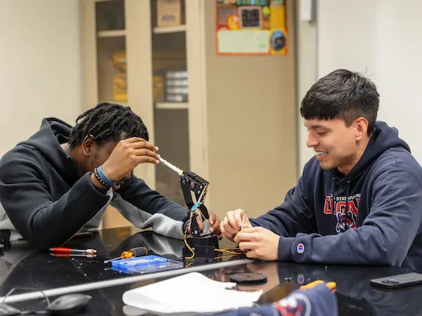 Two students building a robot in a classroom.