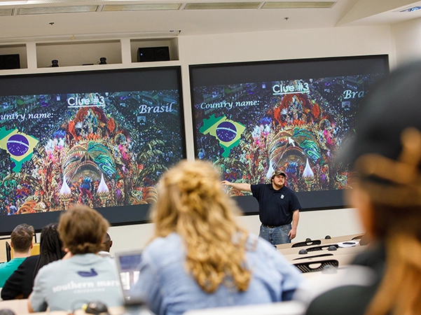 A professor teaching his class in a large study hall.