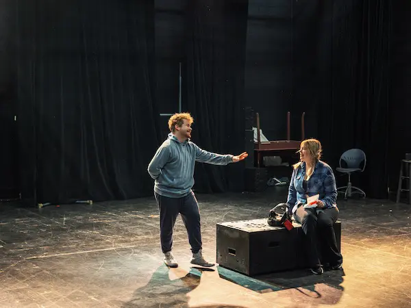 Two students standing together, studying a performance.