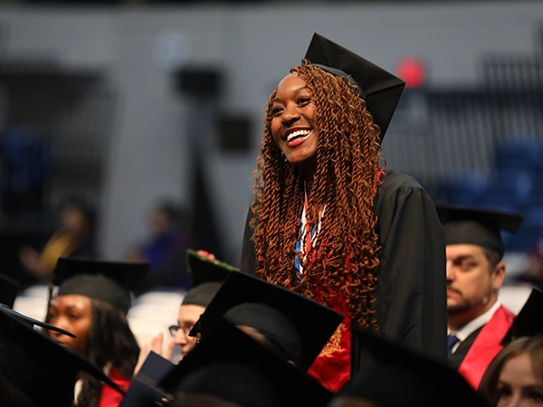 A student smiling happily at her graduation ceremony.