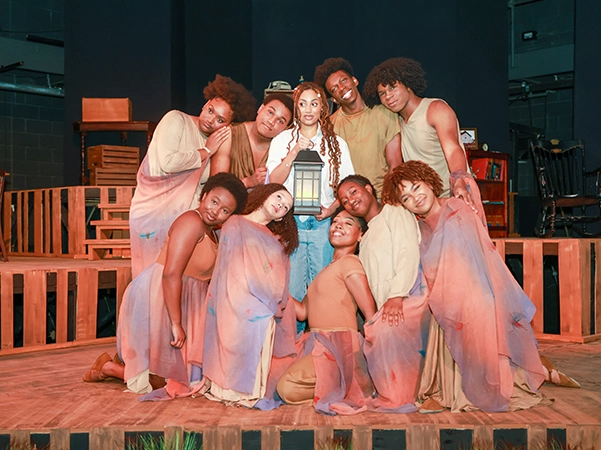 A group of theatre students posing on stage after their performance.