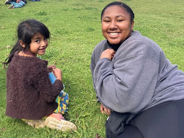 A student studying abroad posing for a picture with a young girl.
