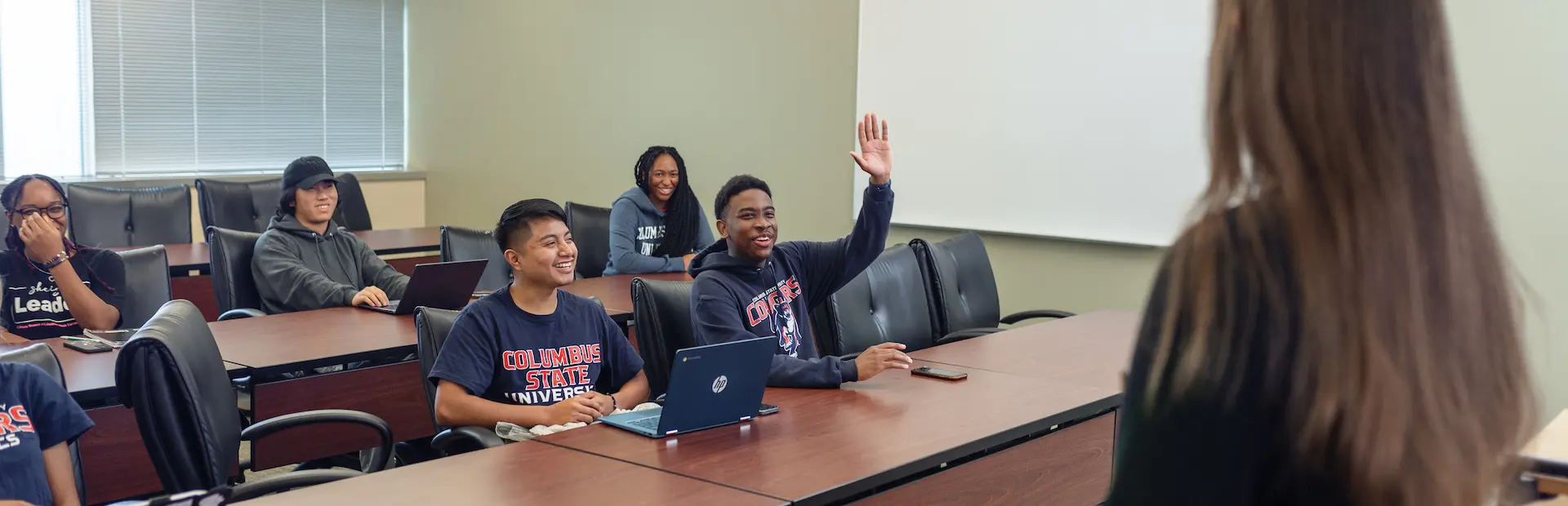 students in a classroom raising hands to answer questions