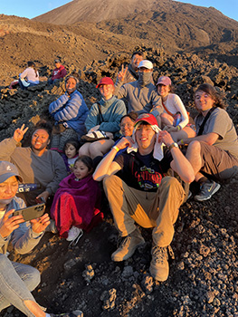 several students sitting a the base of a mountain