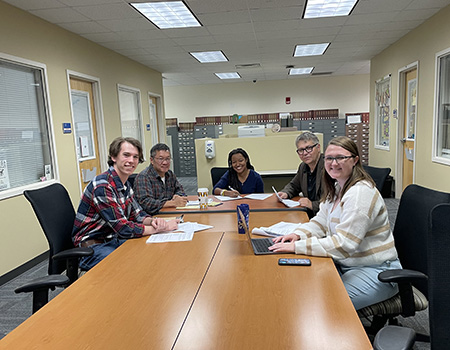 several people sitting together at a wooden conference table