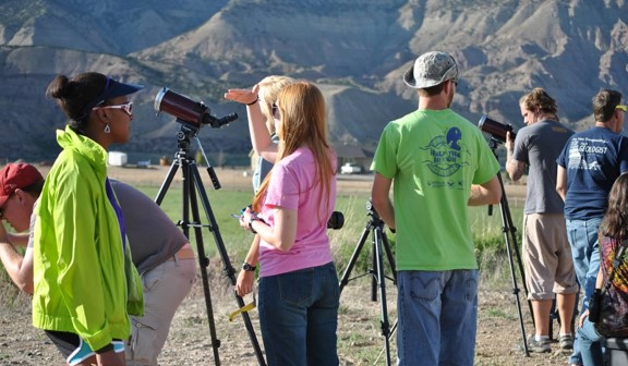Several students standing next to telescopes