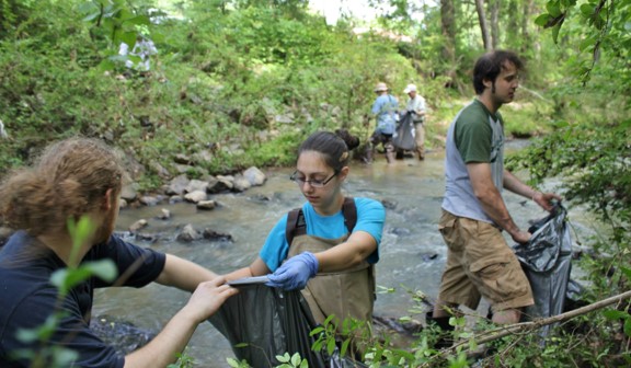 Several male and female students cleaning a river