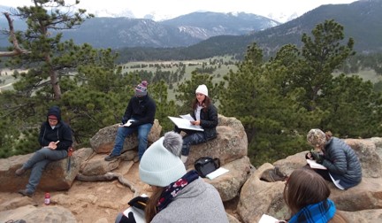 Several students sitting on rocks with paperwork