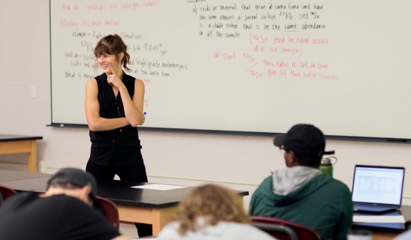 A woman standing in front of a whiteboard in a classroom